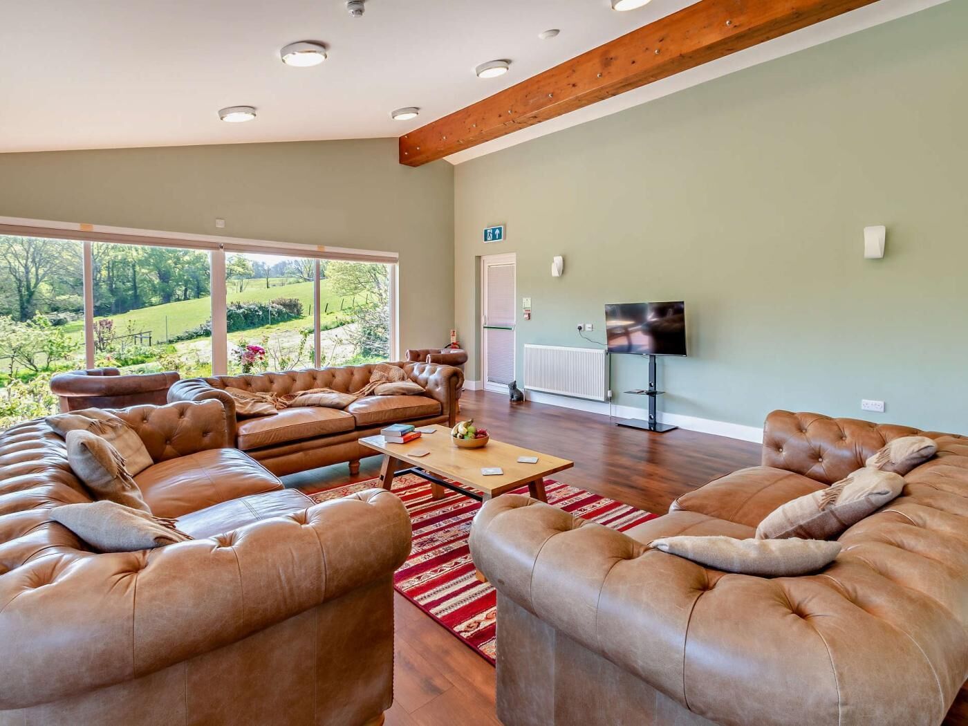 A spacious living room with leather sofas, a coffee table, and a television.