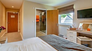 A bedroom with a bed, a desk, a TV, and a window. - 5 Bed in Ventnor (oc-94494) (Godshill)
