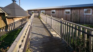 A wooden boardwalk leading to a rustic building labeled 'The Barn' with a metal roof and wooden siding. - 5 Bed in Ventnor (oc-94494) (Godshill)