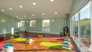 A spacious room with wooden flooring, multiple yoga mats, and a large window with a view of the outdoors. - 5 Bed in Ventnor (oc-94494) (Godshill)