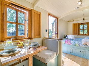 A cozy kitchen with wooden cabinets, a dining table set with dishes, and a view of the outdoors.