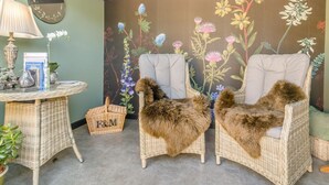 A room with wicker chairs, a table with a lamp, and a floral wall mural. - 1 Bed in Leominster (oc-93060) (Pembridge)