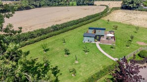 A house with a large lawn, a driveway, and a field in the background. - 1 Bed in Leominster (oc-93060) (Pembridge)