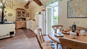 Une cuisine avec des meubles de rangement en bois, une table à manger avec des chaises, un réfrigérateur et une carte accrochée au mur.