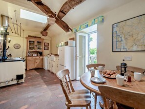 Una cocina con armarios de madera, una mesa de comedor con sillas, un refrigerador y un mapa en la pared.