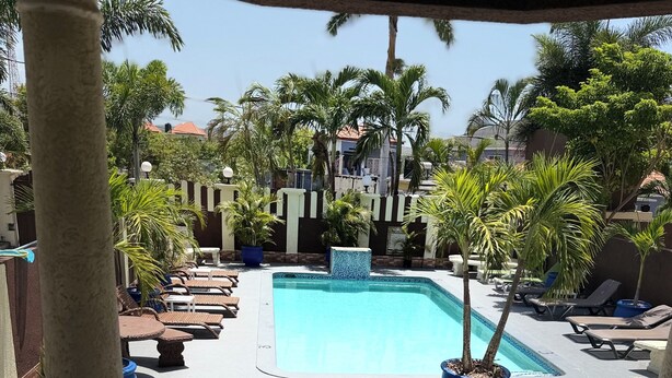 A swimming pool with lounge chairs, palm trees, and a tiled floor. - Relax in luxury and sleep in peace. (Discovery Bay)