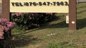 A sign for a guest house named 'Clock Tower' with a telephone number. - Relax in luxury and sleep in peace. (Discovery Bay)