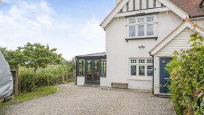 Ein zweistöckiges Haus mit einem Kiesweg, einem Wintergarten und einem Garten.