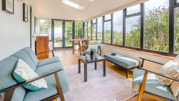 Ein geräumiges Zimmer mit großem Fenster, einer Couch, einem Couchtisch und einem Esstisch.
