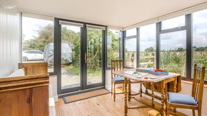 Ein Zimmer mit Holztisch, Stühlen und Blick durch große Fenster.