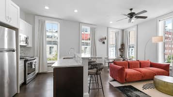 A modern kitchen with a central island, bar stools, and a red sofa.
