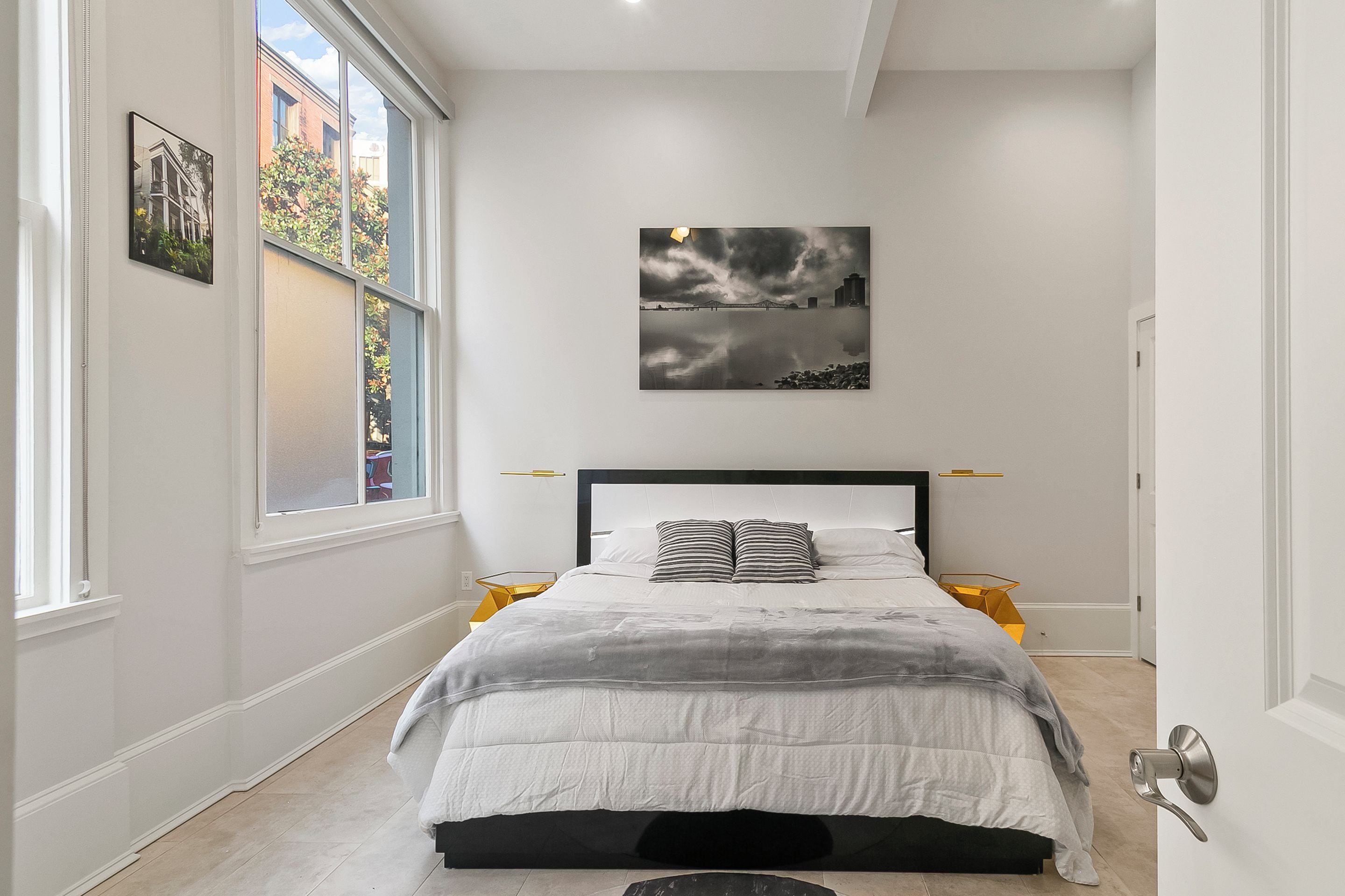 A bedroom with a bed, a window, and a wall-mounted picture.