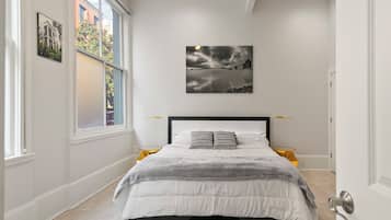 A bedroom with a bed, a window, and a wall-mounted picture.