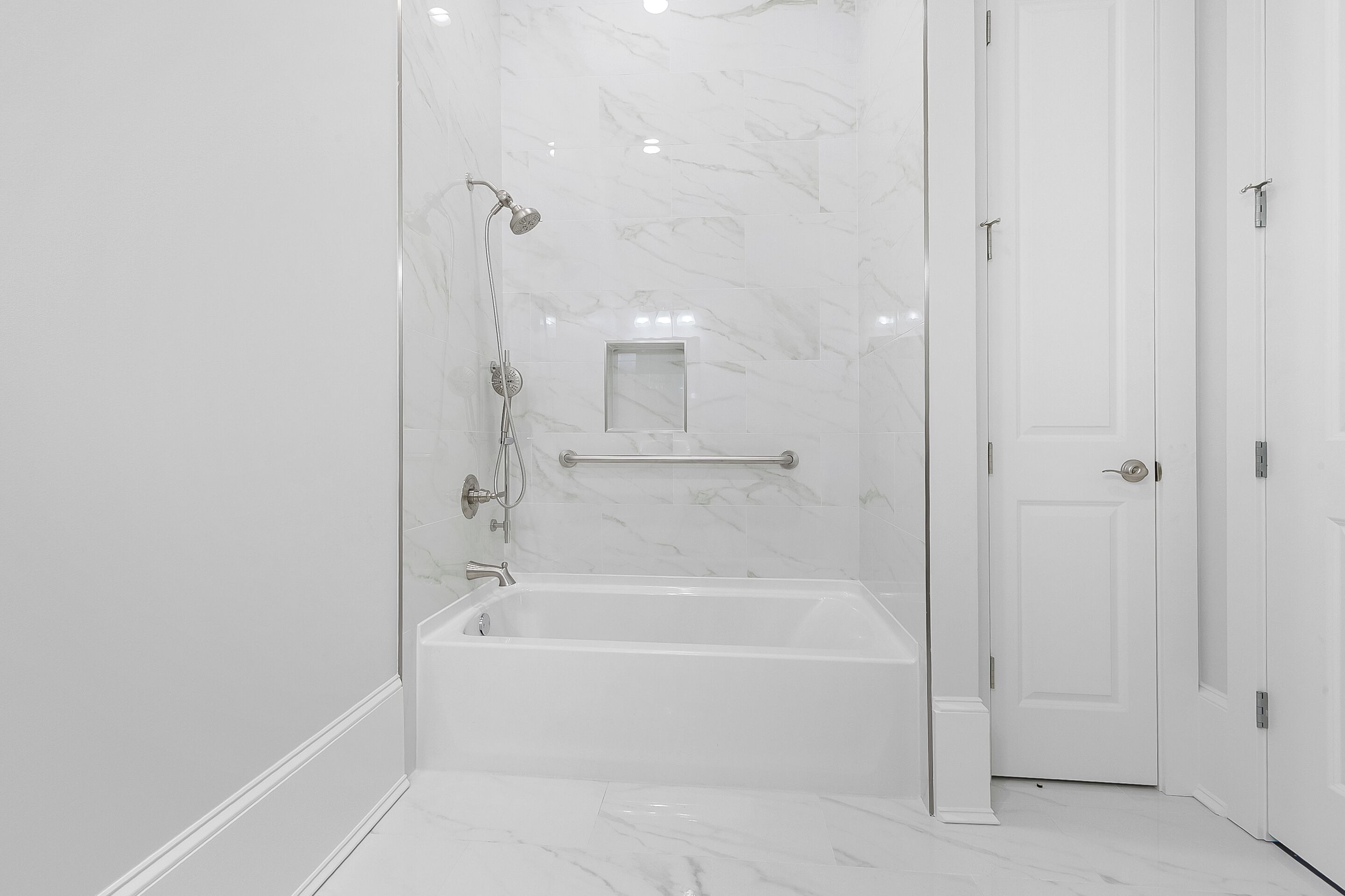 A modern bathroom with a bathtub, a shower area, and a door.