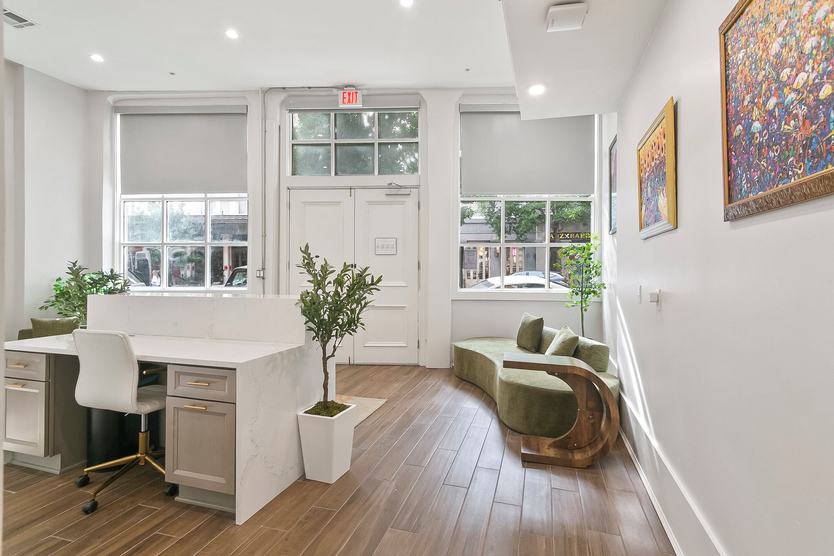 A modern office space with a desk, chair, potted plant, and a curved seating area.