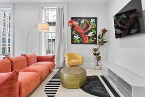 A modern living room with a sofa, a chair, a painting, and a television.