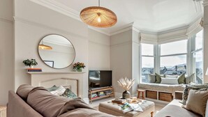 Ein modernes Wohnzimmer mit einem großen Sofa, einem Fernseher, einem Kamin und Blick auf die Stadt durch große Fenster.