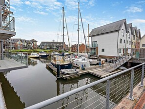 Un port de plaisance avec des bateaux amarrés, un quai et des immeubles résidentiels en arrière-plan.