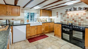 Een keuken met houten kastjes, een vaatwasser, een fornuis en een raam.