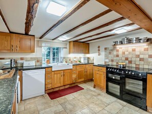 A kitchen with wooden cabinets, a dishwasher, a stove, and a window. - 6 Bed in Filey (oc-94524) (Reighton Gap)