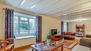 Een woonkamer met een houten salontafel, een bank, een televisie en een boekenkast.