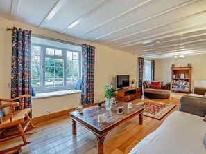 A living room with a wooden coffee table, a sofa, a TV, and a bookshelf. - 6 Bed in Filey (oc-94524) (Reighton Gap)