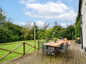 A deck with a table and chairs, surrounded by a wooden fence and lush greenery. - 6 Bed in Filey (oc-94524) (Reighton Gap)