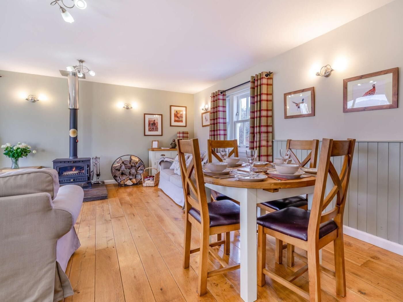 A cozy living room with a fireplace, a dining area with a table set for four, and a sofa.