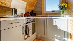 Eine kompakte Küche mit Backofen, Herd und Spüle unter einem Fenster.