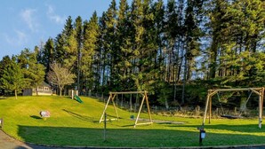 Ein Park mit Schaukeln, einer Rutsche und einem kleinen Gebäude.