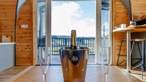 A wooden cabin with a balcony, a champagne bucket, and two glasses.