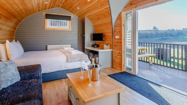 A cozy room with a bed, a small table with glasses, and a TV.