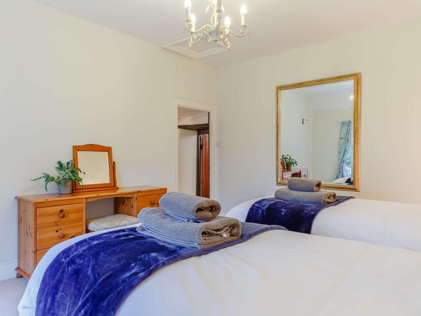 Un dormitorio con cama, cómoda, espejo y candelabro.