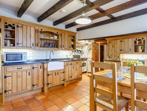 Eine Küche mit Holzausstattung, einer Mikrowelle, einem Spülbecken und einem Essbereich mit Stühlen und Tisch.