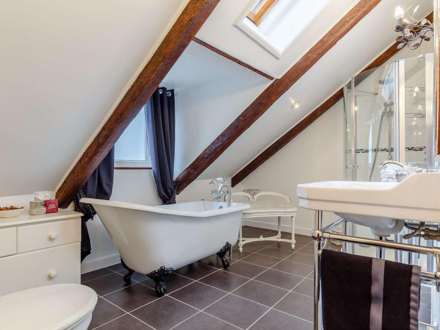 Une salle de bain avec une baignoire sur pieds, un lavabo blanc et une douche à parois de verre.