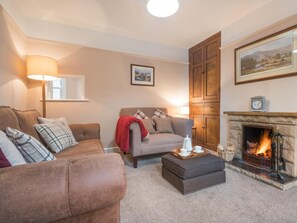 A cozy living room with a fireplace, a sofa, a coffee table, and a lamp. - 2 Bed in Keswick (oc-sz250) (Braithwaite)