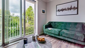 Ein Wohnzimmer mit einem grünen Sofa, einem Monopoly-Spiel und einem gerahmten Stadtbild.