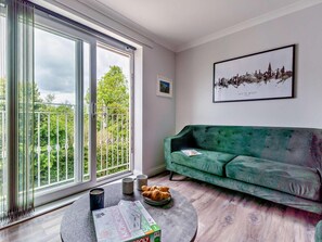 A living room with a green sofa, a Monopoly board game, and a framed cityscape picture. - 2 Bed in Freshwater (oc-94561) (Freshwater)