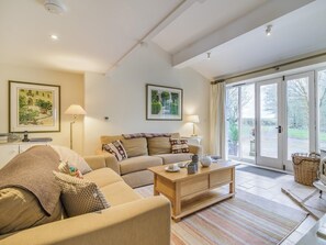 Ein geräumiges Wohnzimmer mit einer Couch, einem Couchtisch und einem großen Fenster mit Blick ins Freie.