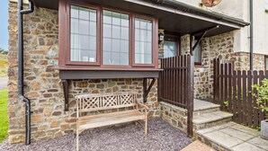 A stone building with a wooden bench, a gate, and a satellite dish. - 2 Bed in Woolacombe (oc-westd) (Woolacombe)