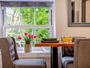 A dining area with a table, chairs, and a window with a view of greenery. - 2 Bed in Kendal (oc-94582) (Brigsteer)