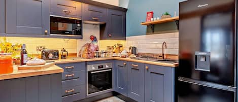 Una cucina moderna con mobili grigi, un frigorifero nero e un pavimento in pietra.