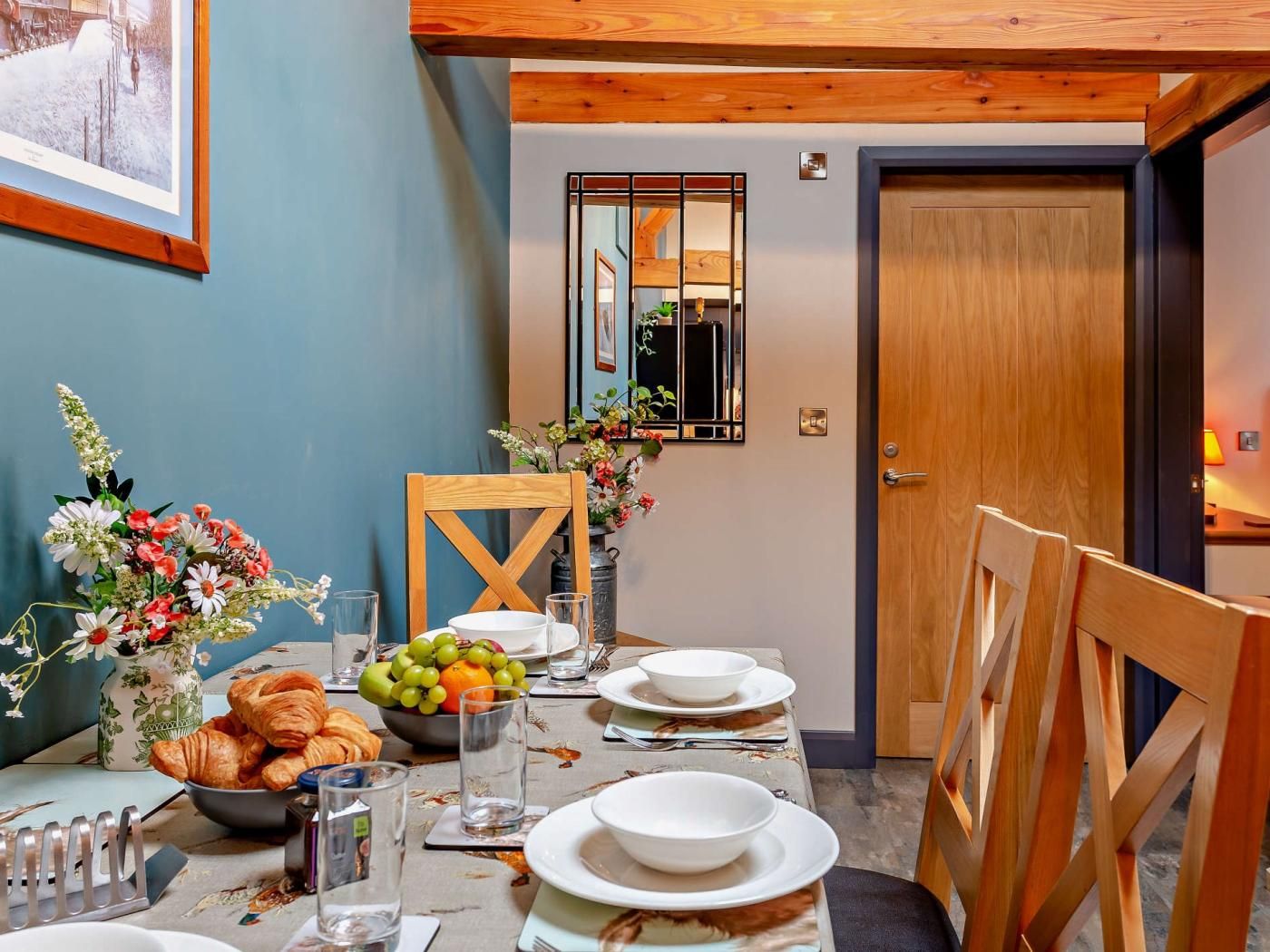A dining area with a table set for four, including plates, glasses, and a bowl of fruit.