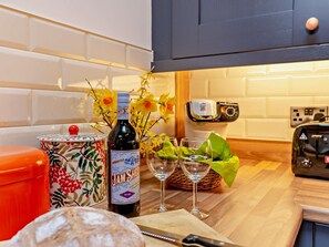 Eine Küche mit einer Weinflasche, Gläsern, einem Brotlaib und einem Toaster.