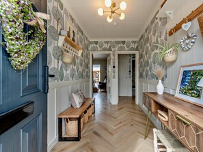 A hallway with patterned wallpaper, a wooden bench, baskets, a hanging plant, and a wall-mounted shelf. - 3 Bed in Aberaeron (oc-88788) (Aberarth)