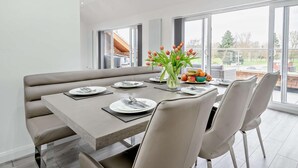 Een moderne eethoek met een grote tafel, beklede bankjes en uitzicht op de omgeving.