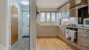A modern kitchen with wooden flooring, a built-in oven, and a microwave. - 2 Bed in Wareham (oc-94520) (West Lulworth)