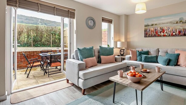 A living room with a sofa, a coffee table, and a dining area with chairs and a table. - 2 Bed in Wareham (oc-94520) (West Lulworth)