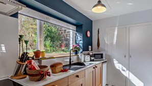 Une cuisine moderne dotée d’une grande fenêtre, de meubles en bois, d’un four à micro-ondes et d’un évier.