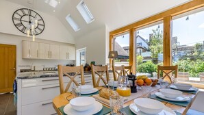 A modern kitchen with white cabinets, a large clock, and a dining area with a table set for breakfast. - 5 Bed in Telford (oc-72844) (New Works)